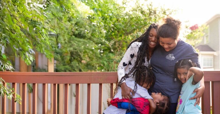 Family sharing a happy embrace on a sunny day at Charlotte Family Housing