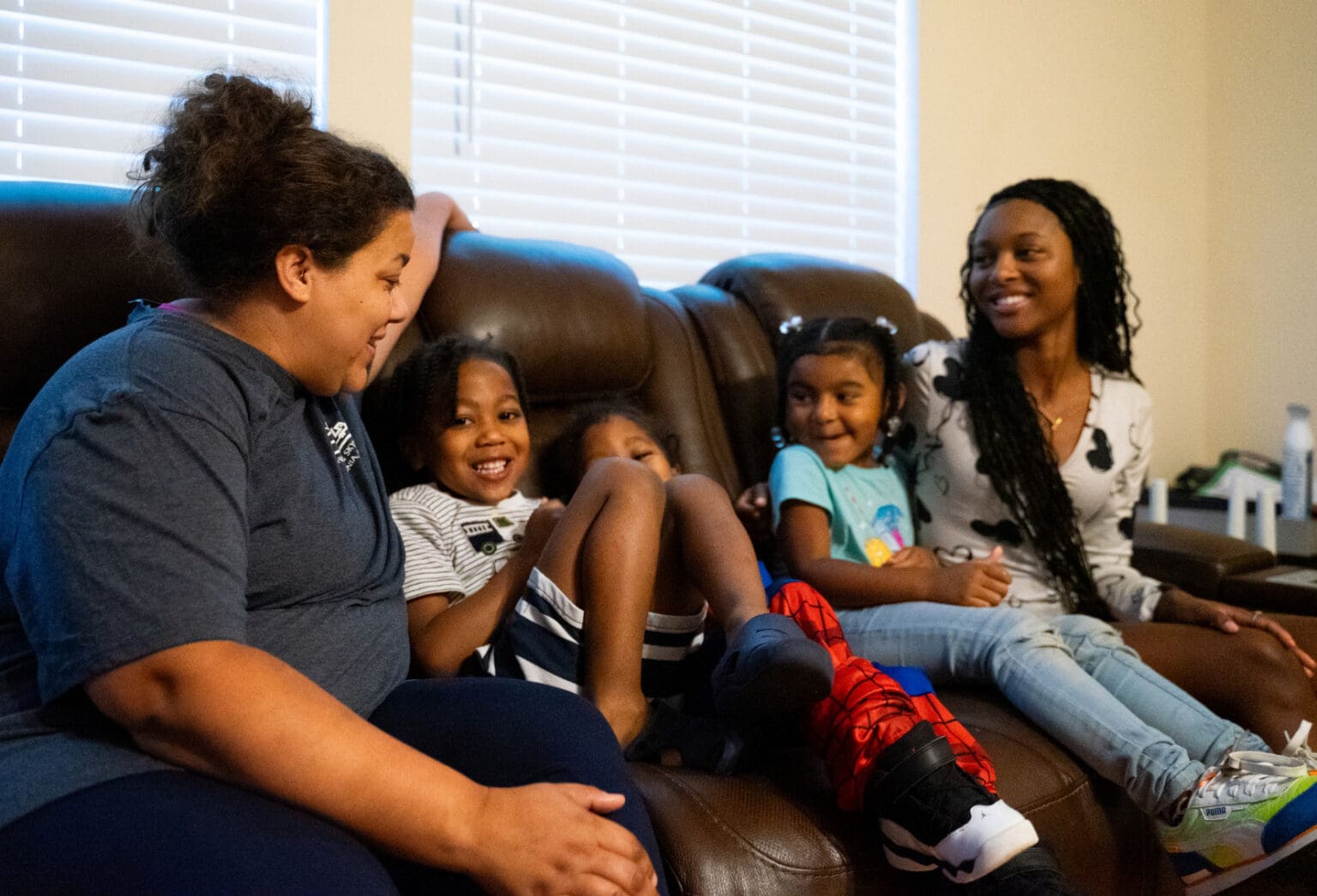 Family laughing together on the couch at Charlotte Family Housing
