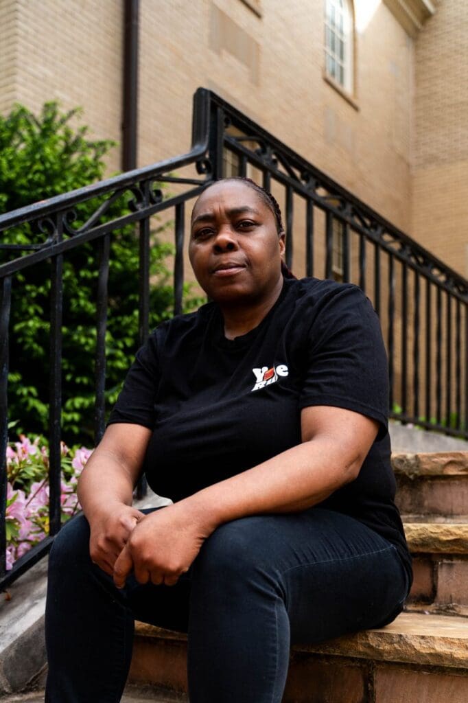 Person sitting on outdoor stone steps by railing.